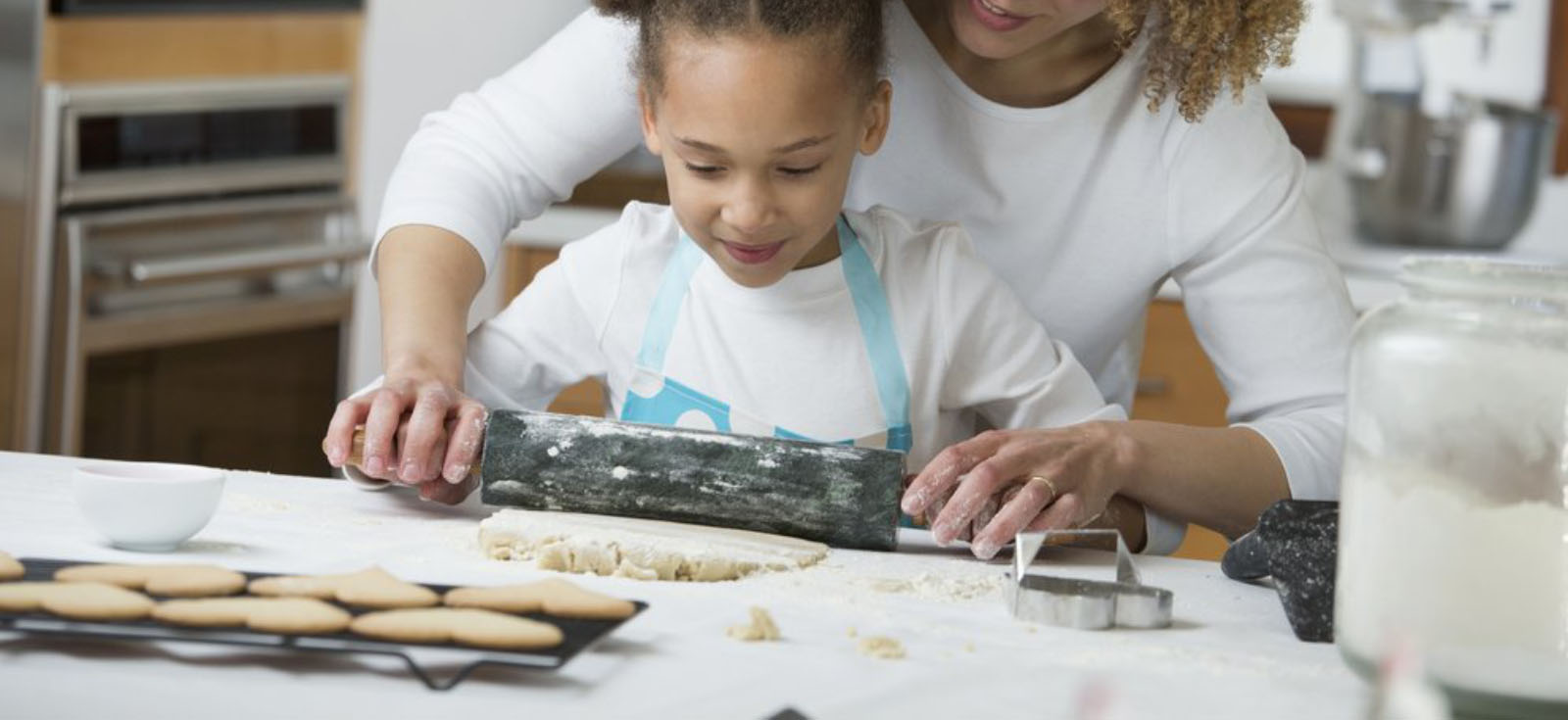 A woman and child with a rolling pin making cookies