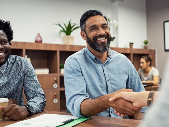 Two people shaking hands in office