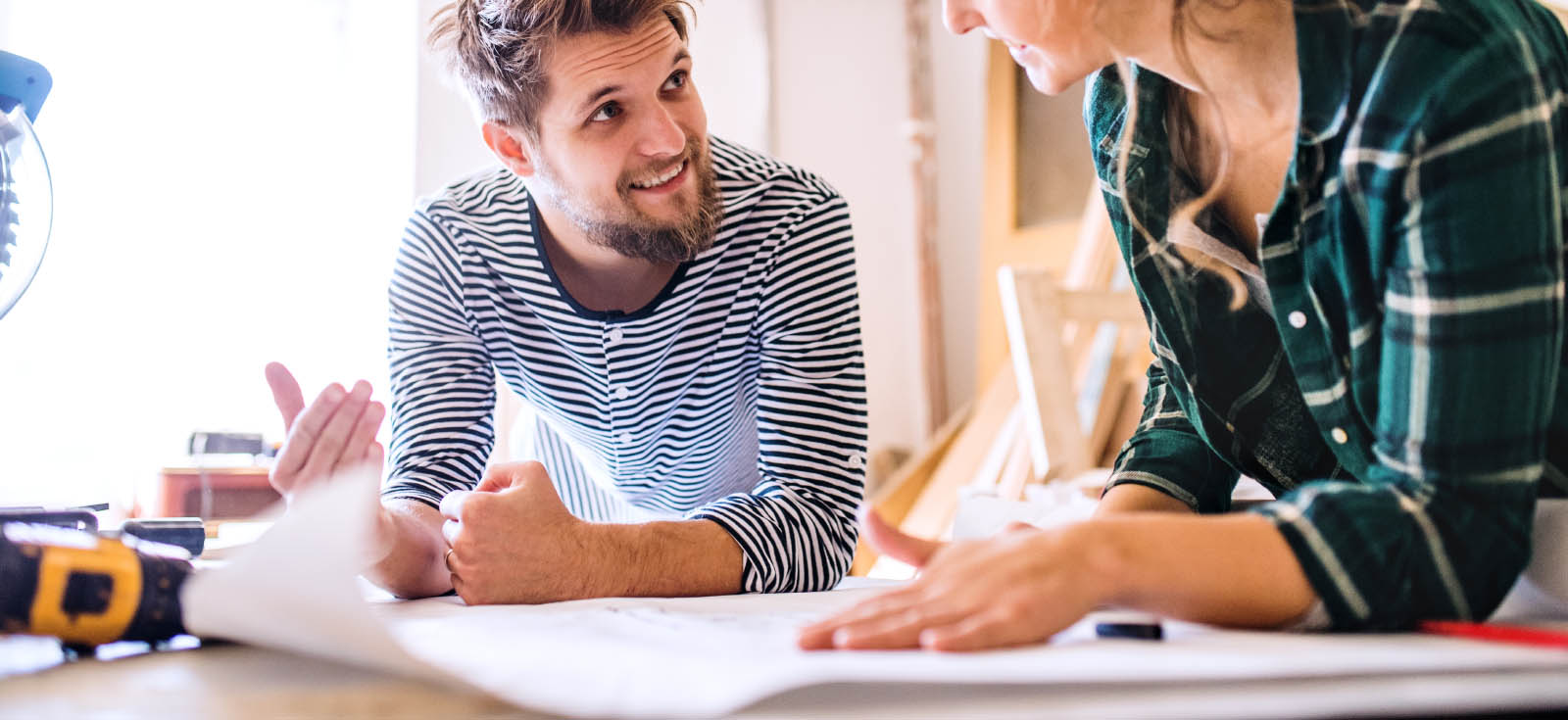 Two people talking over plans on paper.